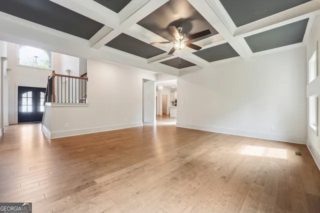 a view of an empty room with wooden floor and a ceiling fan