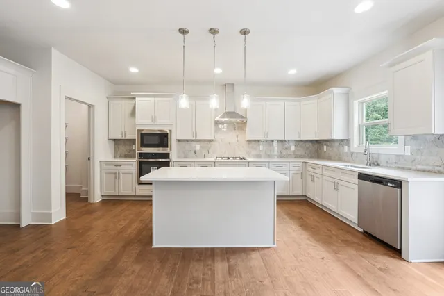 a kitchen with stainless steel appliances granite countertop a sink a stove a refrigerator and island with wooden floor