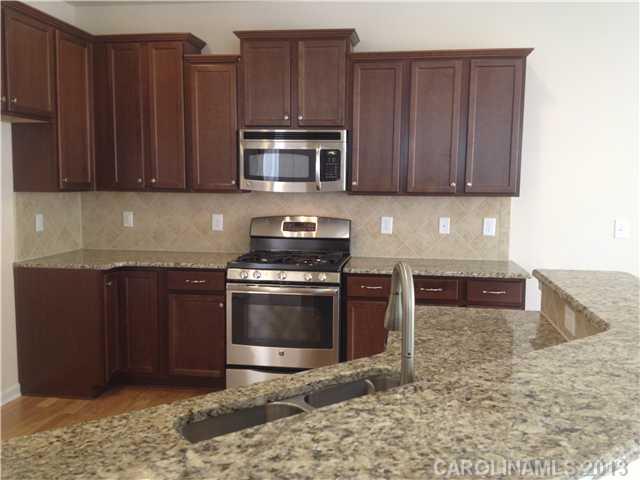 78062 Rillstone Drive, Unit LOT193 Lancaster, SC 29720 - Photo 3 of 15 a kitchen with stainless steel appliances granite countertop wooden cabinets a stove and a microwave