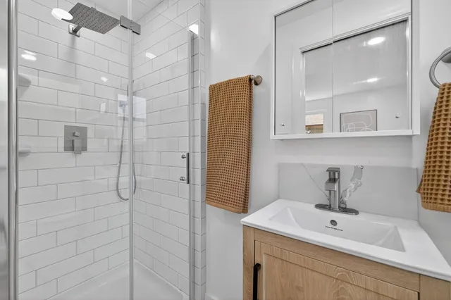 a bathroom with a sink shower and a mirror
