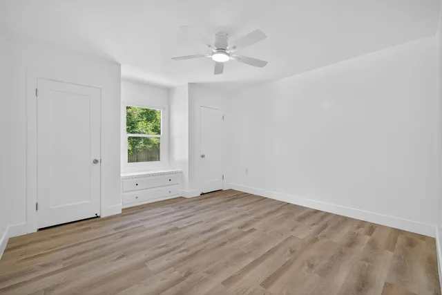 a view of an empty room with wooden floor and a window