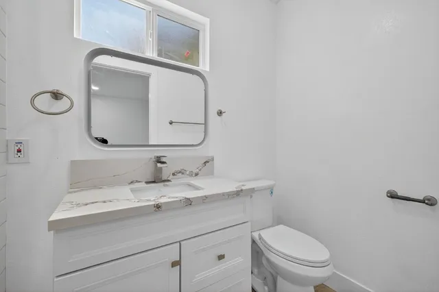 a bathroom with a toilet sink vanity and mirror