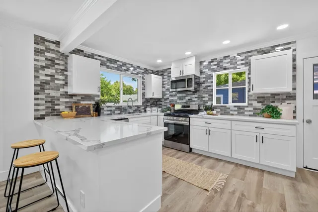 a kitchen with stainless steel appliances kitchen island granite countertop a stove a sink and a refrigerator