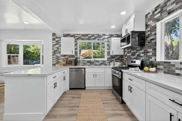 a kitchen with stainless steel appliances granite countertop a stove a sink and a microwave