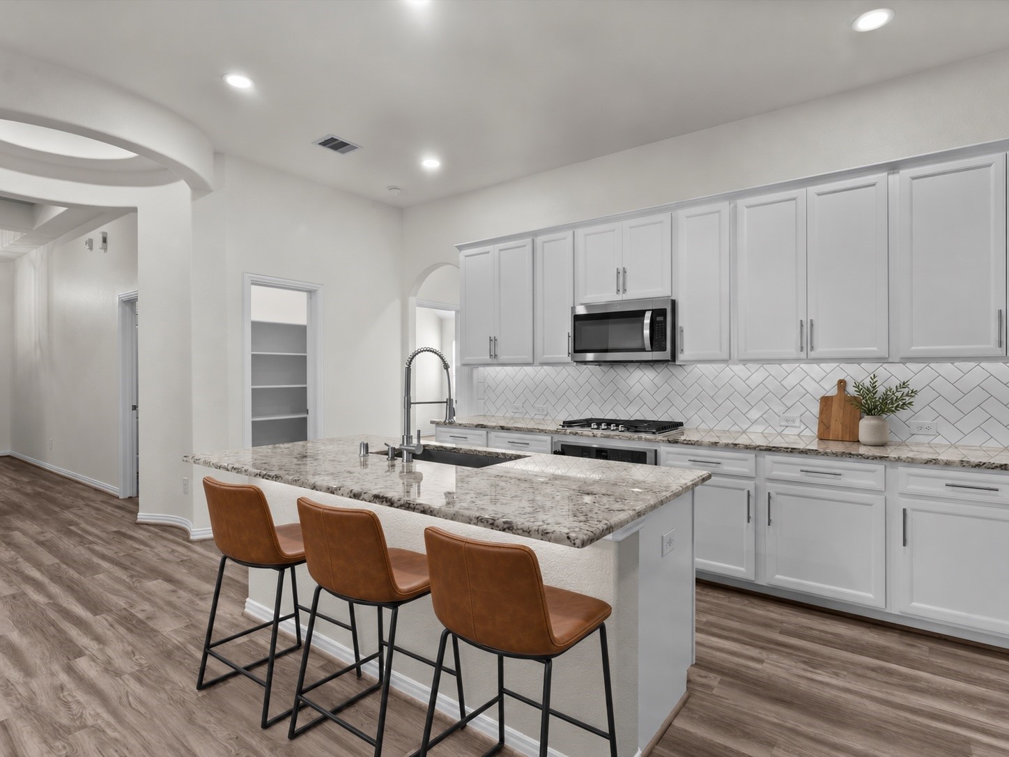 4746 Misty Ranch Drive Spring, TX 77386 - Photo 14 of 49 Virtually staged to showcase the space, the kitchen features a herringbone tile backsplash, granite countertops, stainless steel appliances, a gas range, and a spacious island with room for bar seating.