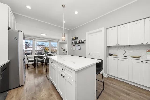 a kitchen with a stove a sink a refrigerator and white cabinets with wooden floor