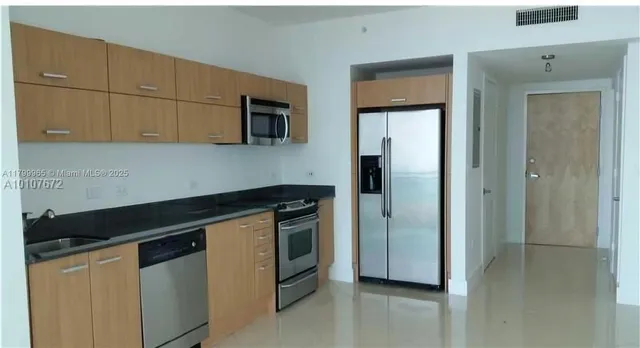 a kitchen with stainless steel appliances granite countertop white cabinets and refrigerator