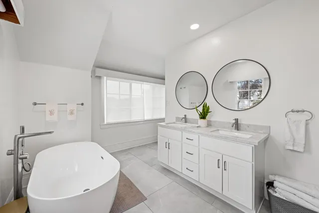 a bathroom with a toilet a sink a mirror and a window