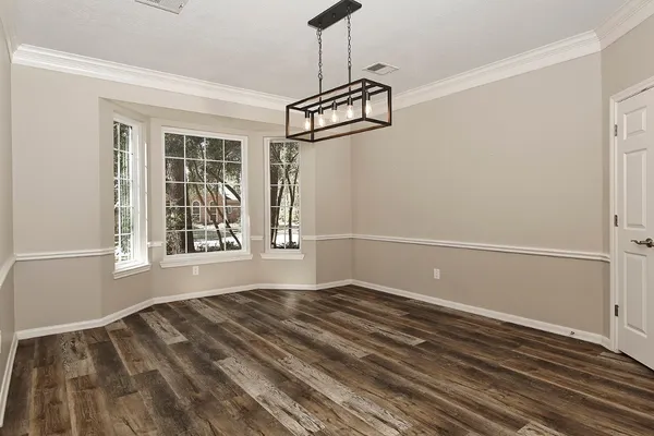 a view of a dining room and livingroom with furniture wooden floor kitchen chandelier