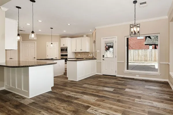 a view of an empty room with wooden floor and a fireplace