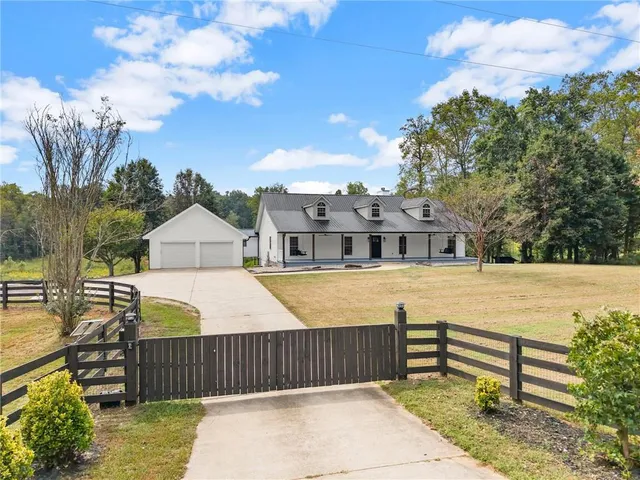 a view of a white house with a swimming pool and a yard