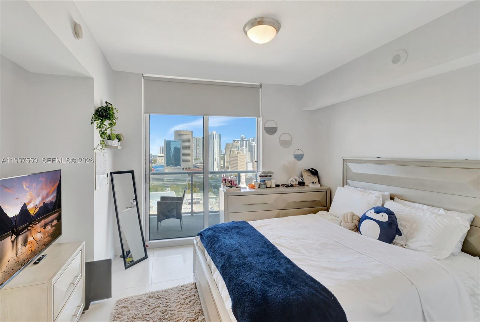 185 Southwest 7th Street, Unit 2303 Miami, FL 33130 - Photo 16 of 40 a bedroom with a bed a flat screen tv and a couch
