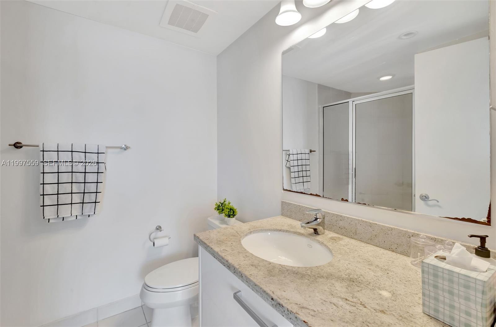 185 Southwest 7th Street, Unit 2303 Miami, FL 33130 - Photo 19 of 40 a bathroom with a granite countertop sink and a toilet