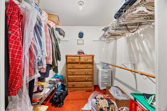 a view of walk in closet with clothes and shoes