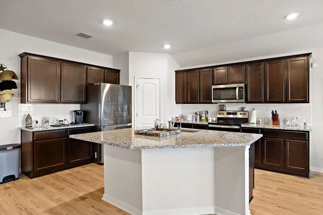 a kitchen with stainless steel appliances granite countertop a stove top oven a refrigerator a sink and dishwasher