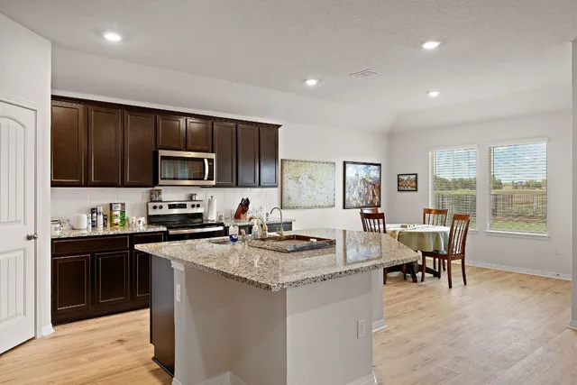 a kitchen with a stove a sink a dining table and chairs
