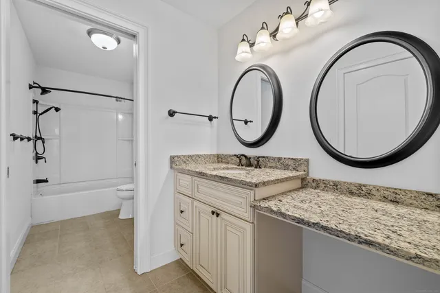 a bathroom with a granite countertop toilet sink and mirror