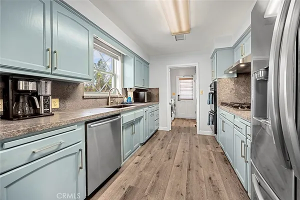 a kitchen with granite countertop stainless steel appliances cabinets a sink and a counter top space