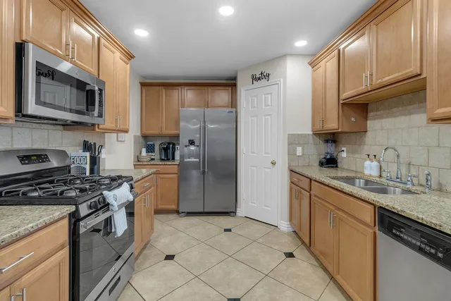 a kitchen with stainless steel appliances granite countertop a stove a sink dishwasher a refrigerator and a microwave