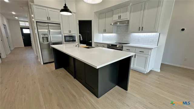 a kitchen with stainless steel appliances a sink a stove a refrigerator and cabinets