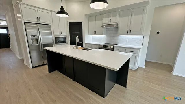 a kitchen with refrigerator cabinets and wooden floor
