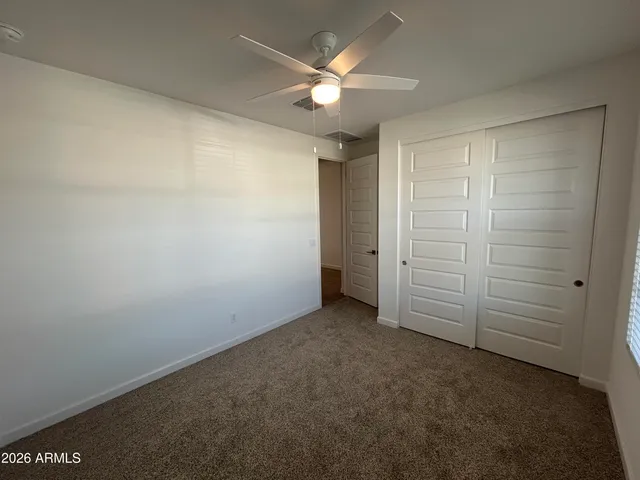 an empty room with closet and fan