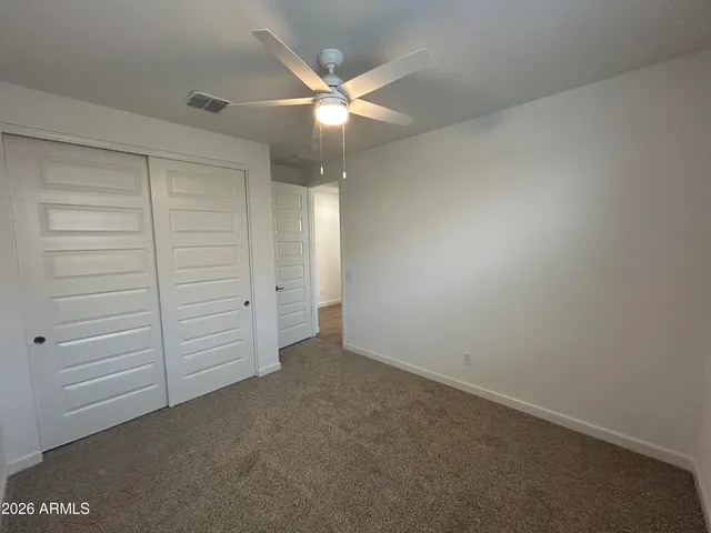 an empty room with closet and fan
