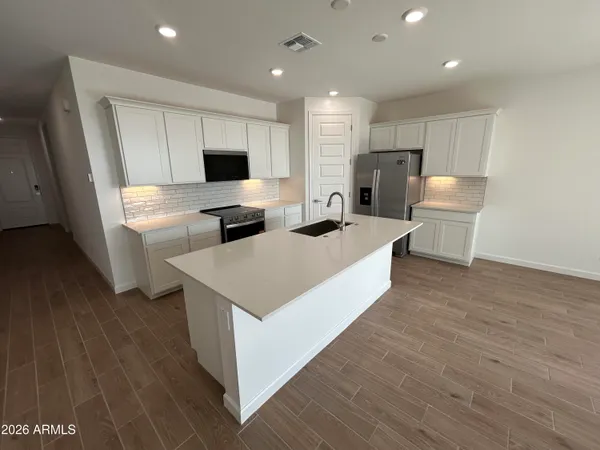 a living room with stainless steel appliances furniture wooden floor and a view of kitchen