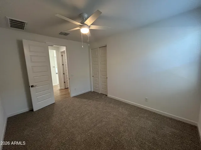 an empty room with closet and a chandelier fan
