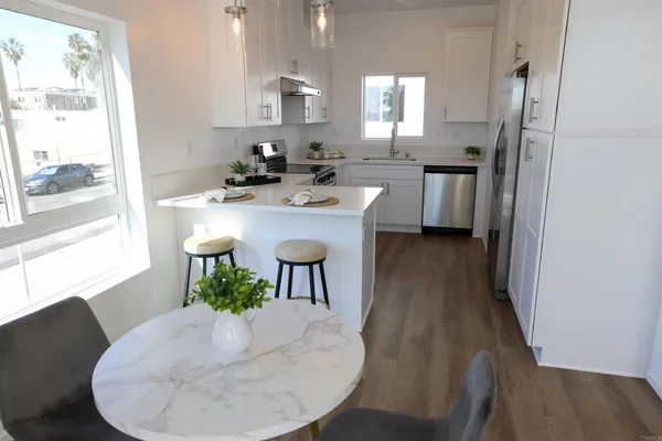 a kitchen with stainless steel appliances granite countertop a sink a window a dining table and chairs