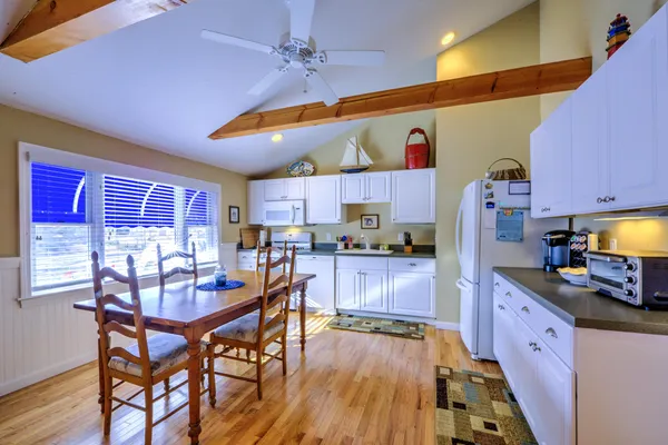 a kitchen with stainless steel appliances kitchen island granite countertop a table chairs in it and wooden floors