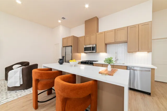 a kitchen with stainless steel appliances granite countertop a sink a stove a refrigerator cabinets and chairs