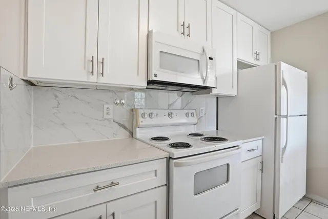 a kitchen with stainless steel appliances granite countertop a refrigerator sink and white cabinets