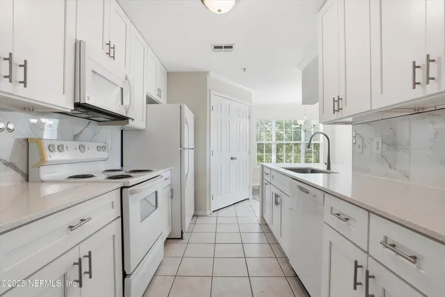 a kitchen with white cabinets and sink