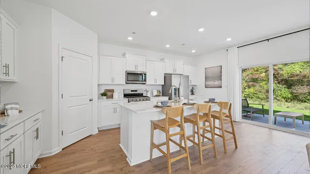 a kitchen with stainless steel appliances granite countertop a refrigerator a sink dishwasher a stove and white cabinets with wooden floor