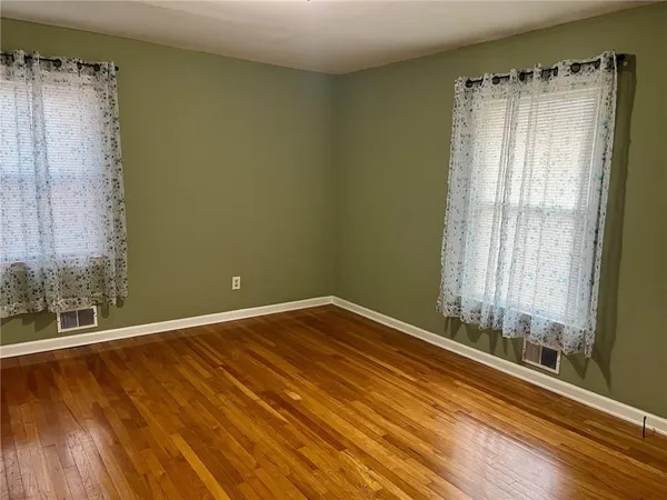 a view of an empty room with wooden floor & closet