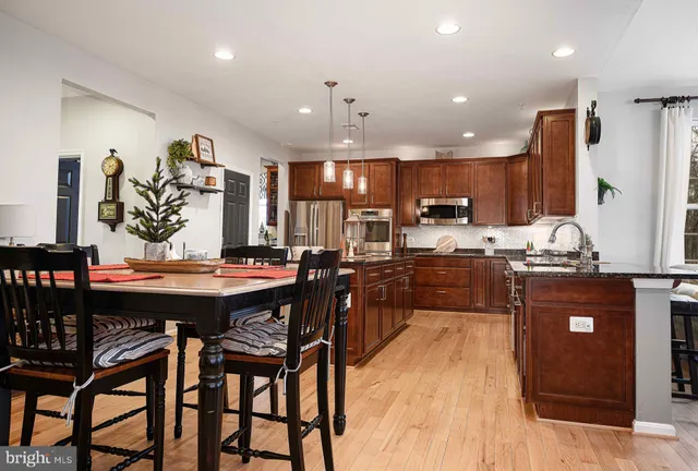 a kitchen with stainless steel appliances kitchen island granite countertop a table chairs and a refrigerator