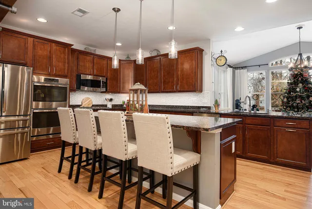 a kitchen with stainless steel appliances kitchen island granite countertop a kitchen island a stove a sink a dining table and chairs