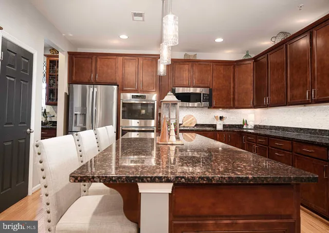 a kitchen with kitchen island granite countertop a sink a counter top space appliances and cabinets