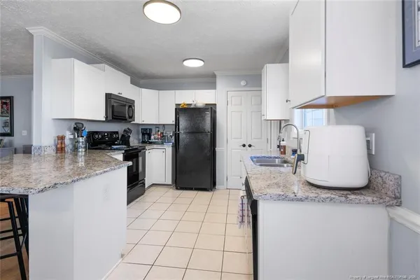 a kitchen with granite countertop a sink a stove a refrigerator a counter top space and cabinets