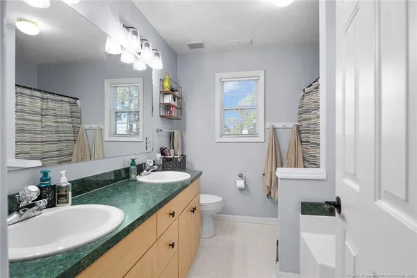 a bathroom with a granite countertop sink a toilet a mirror a vanity and window