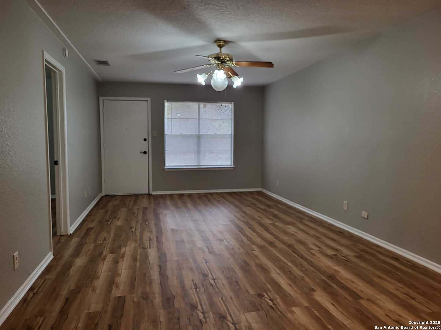 1051 Country Club Drive, Unit 19 Seguin, TX 78155 - Photo 5 of 17 wooden floor in an empty room with a window