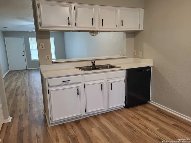 a kitchen with granite countertop a sink cabinets and stainless steel appliances