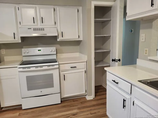 a kitchen with granite countertop white cabinets and white appliances