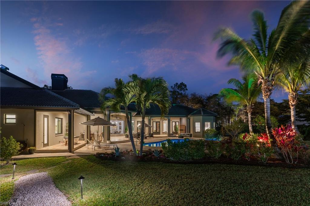 6610 Sable Ridge Lane Naples, FL 34109 - Photo 2 of 47 a front view of a house with a garden and yard