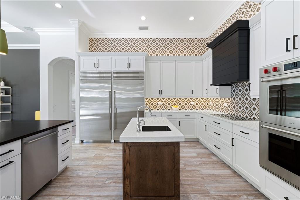 6610 Sable Ridge Lane Naples, FL 34109 - Photo 5 of 47 a kitchen with stainless steel appliances kitchen island granite countertop a stove a sink and a microwave