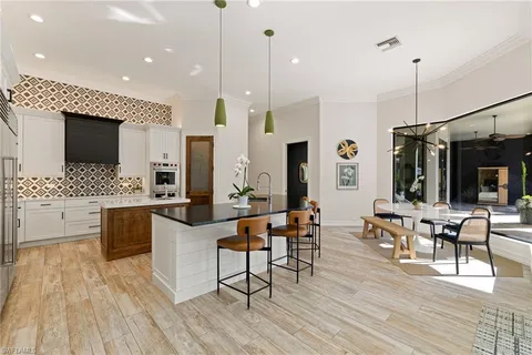 a kitchen with stainless steel appliances kitchen island granite countertop a stove a sink a dining table and chairs