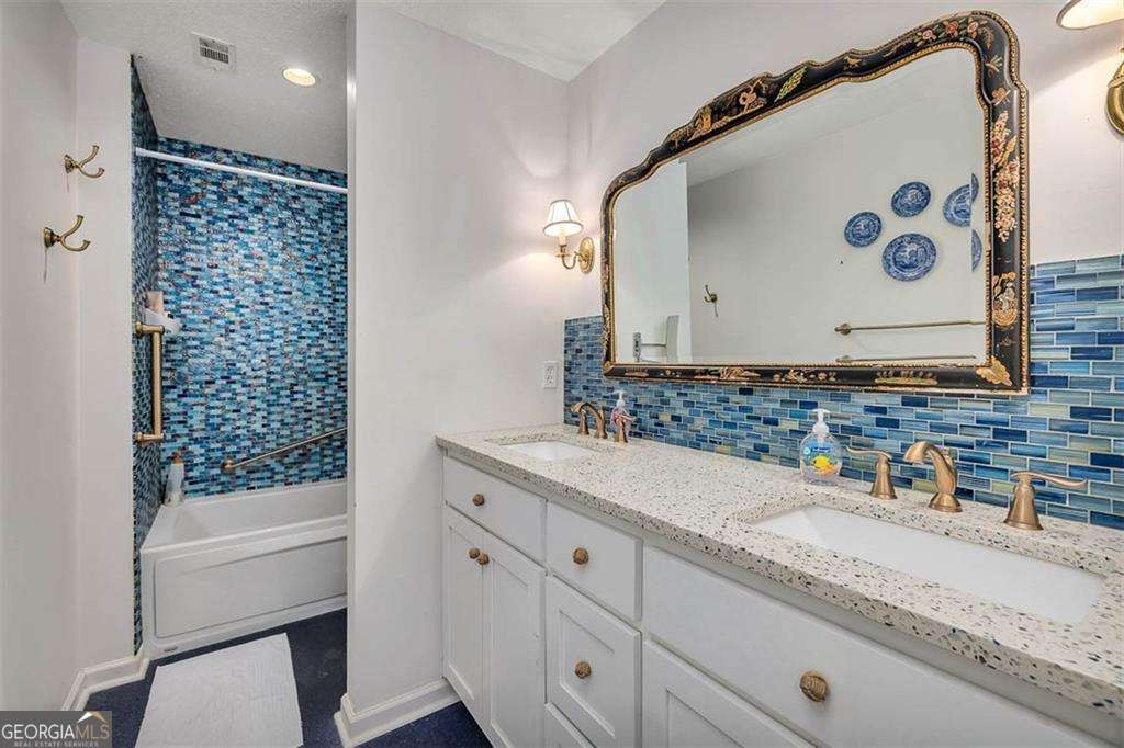 548 Oglethorpe Avenue, Unit 11 St. Simons, GA 31522 - Photo 16 of 25 a bathroom with a granite countertop sink and a mirror