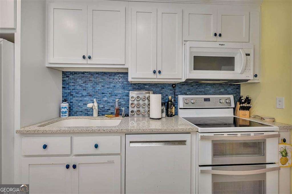 548 Oglethorpe Avenue, Unit 11 St. Simons, GA 31522 - Photo 3 of 25 a kitchen with granite countertop white cabinets and white appliances