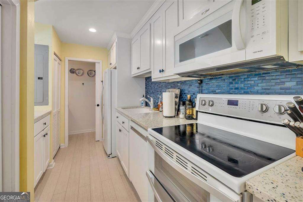548 Oglethorpe Avenue, Unit 11 St. Simons, GA 31522 - Photo 9 of 25 a kitchen with stainless steel appliances granite countertop a stove and a microwave